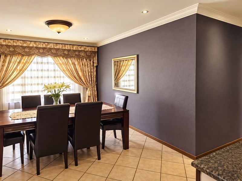 A well-maintained dining room featuring ceramic floor tiles, recessed downlighting, and decorative ceiling cornicing.