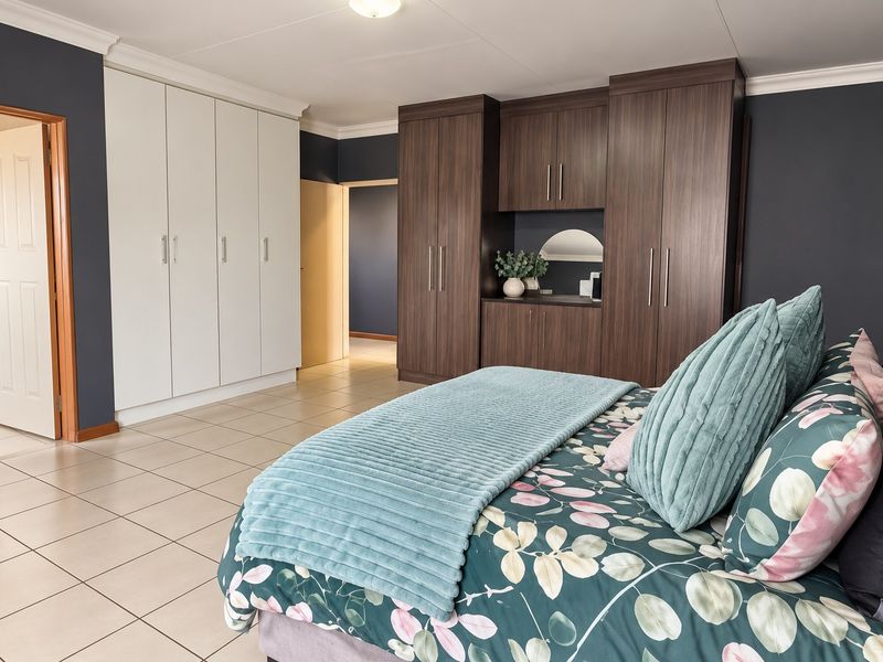 Spacious bedroom featuring extensive built-in cabinetry, neutral tiled flooring, and dark accent walls, providing ample storage and a modern aesthetic.