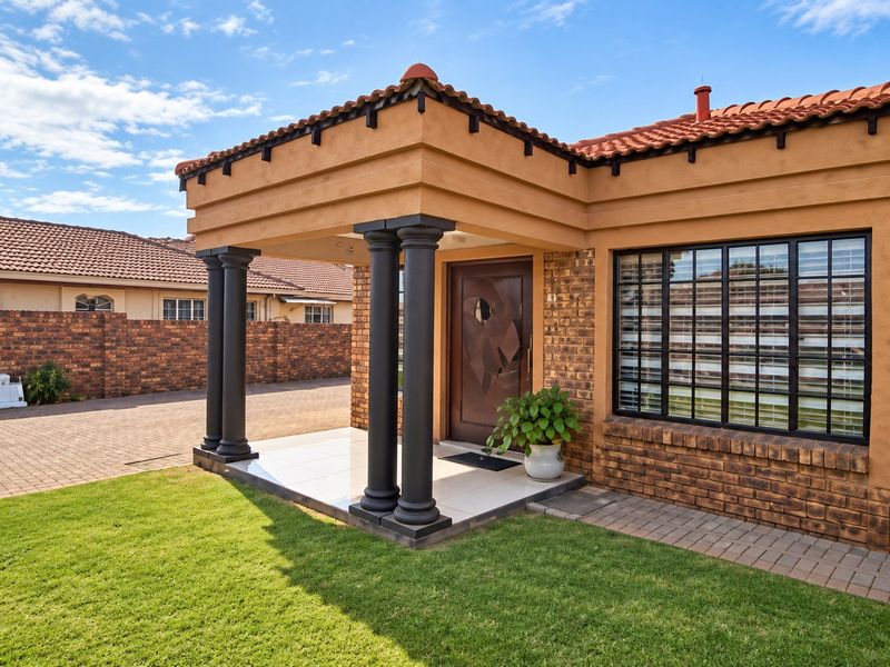Front entrance of a face brick house featuring a covered porch with decorative columns, tiled flooring, and a well-maintained lawn.