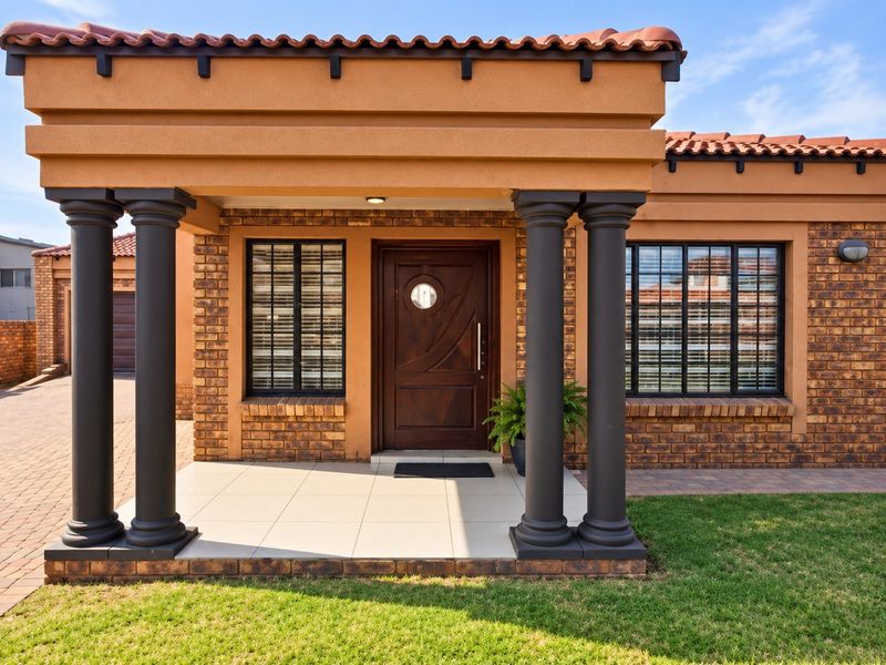 A well-maintained front entrance featuring a covered porch, decorative columns, and a solid timber door with a circular window detail.