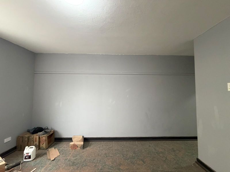 An empty bedroom featuring tiled flooring and grey painted walls, requiring minor cosmetic touch-ups to restore its appeal.