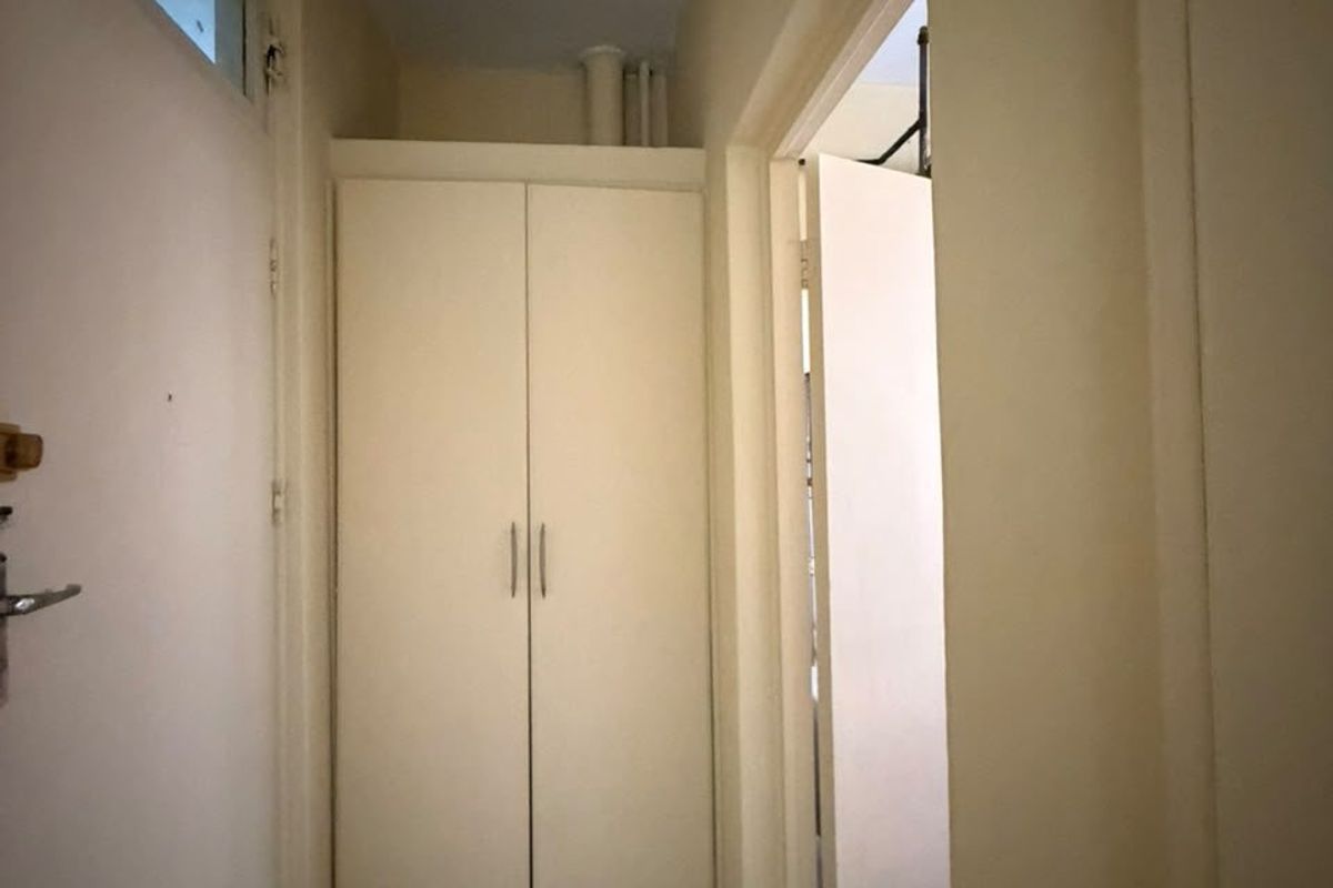 A functional hallway featuring a built-in storage cupboard and a transom window above the door frame.