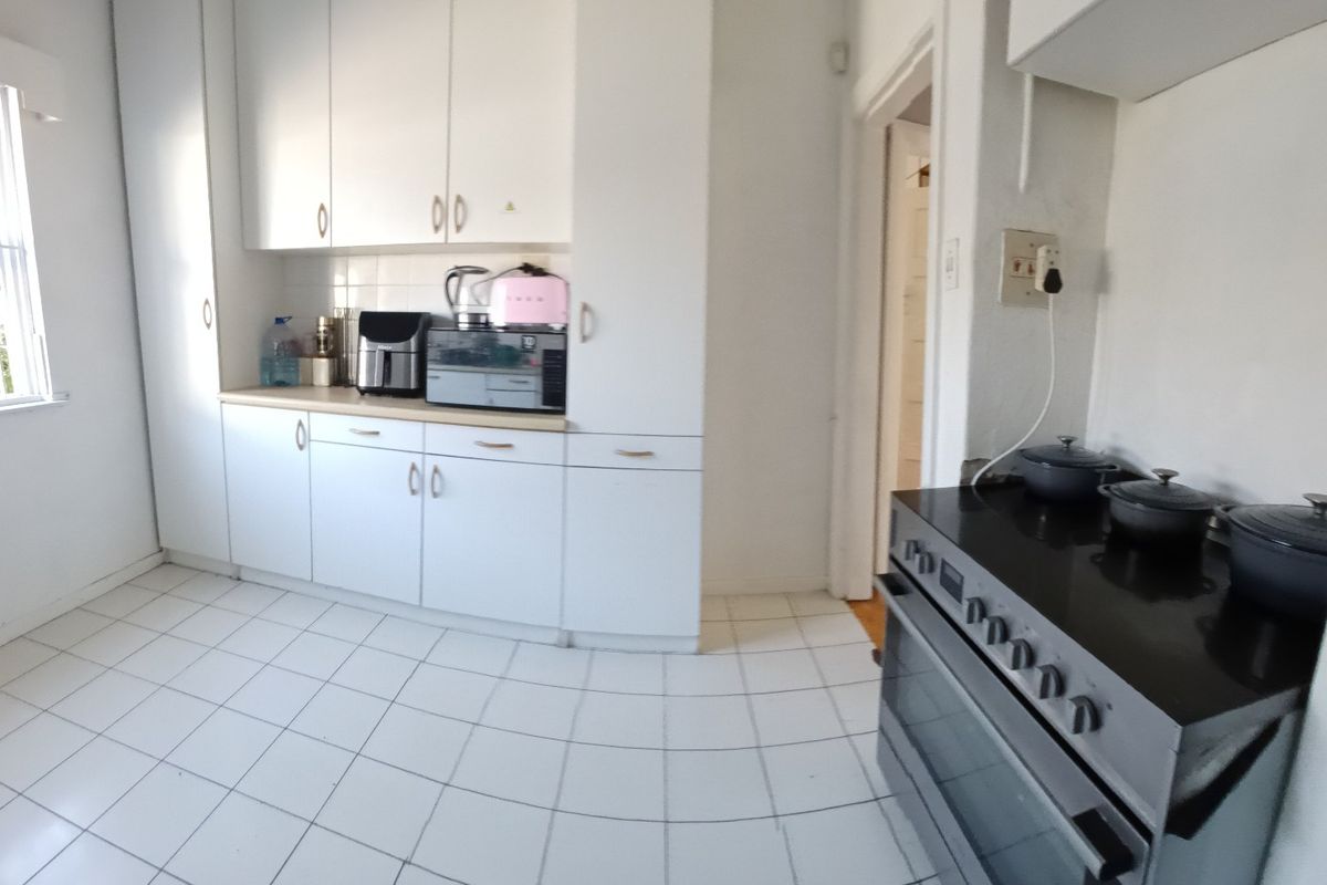 A functional kitchen featuring white cabinetry, tiled flooring, and a freestanding stove, offering a clean and practical workspace.