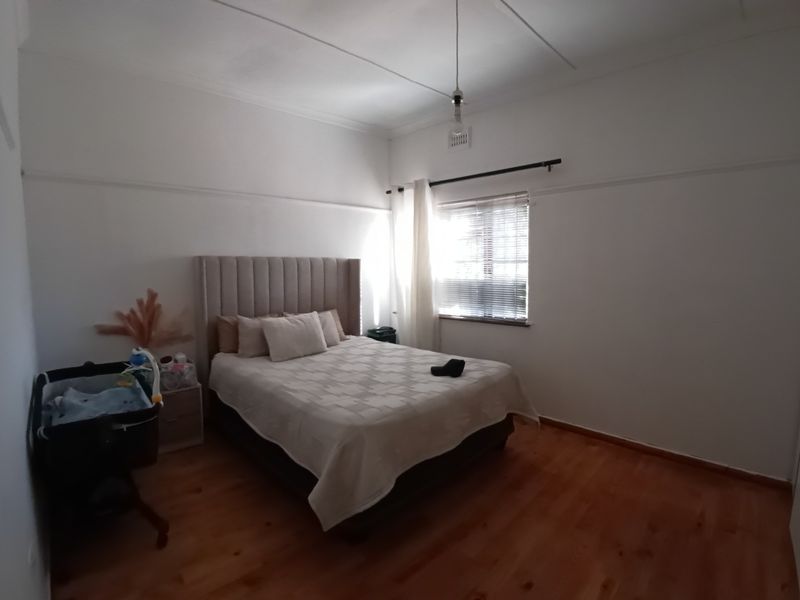 A bedroom featuring timber flooring, built-in cupboards, and a picture rail, offering a neutral canvas for personalization.