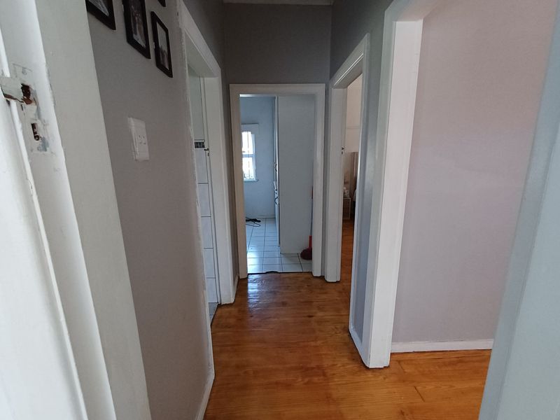A central hallway featuring polished hardwood flooring and multiple doorways leading to adjacent rooms, providing access throughout the home.