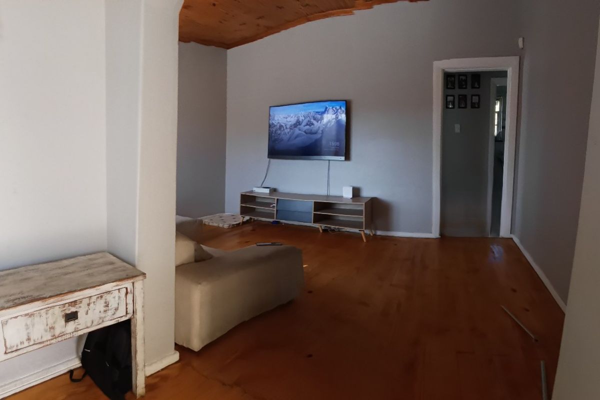 A living room featuring timber flooring and a vaulted timber ceiling, connected to adjacent spaces via an architectural archway.