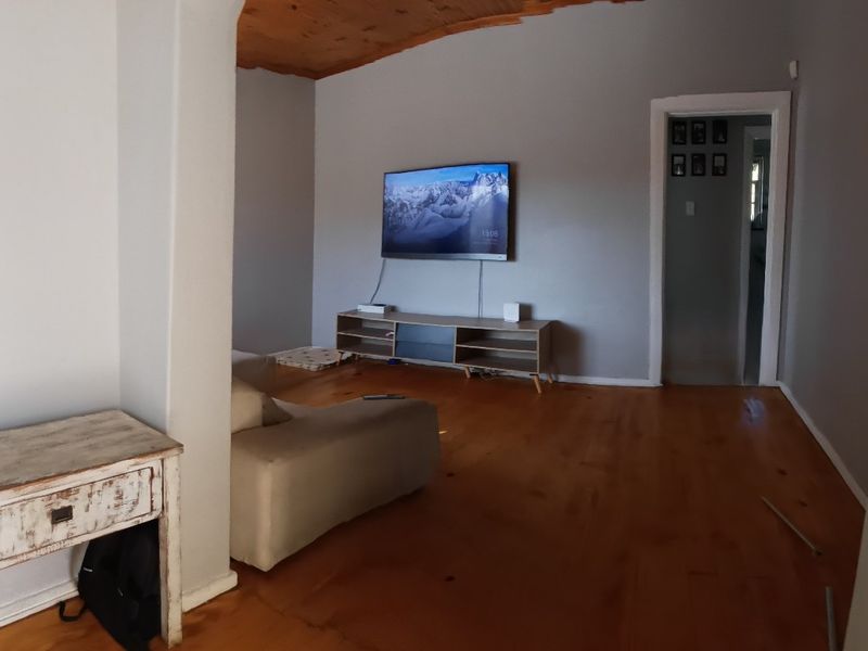 A living room featuring timber flooring and a vaulted timber ceiling, connected to adjacent spaces via an architectural archway.