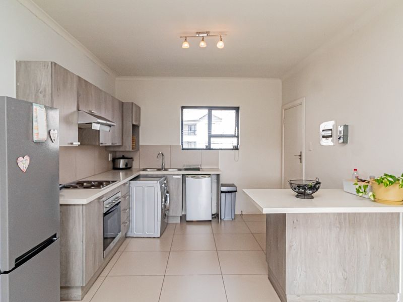A functional kitchen featuring modern wood-look cabinetry, stone-style countertops, a built-in oven with hob, and a convenient breakfast bar area.