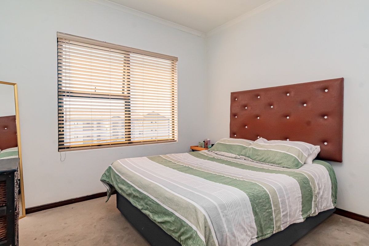 A bedroom featuring carpeted flooring, venetian blinds, and neutral wall finishes, providing a functional space for rest.