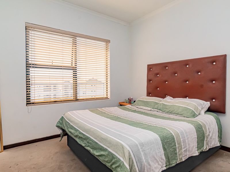 A bedroom featuring carpeted flooring, venetian blinds, and neutral wall finishes, providing a functional space for rest.