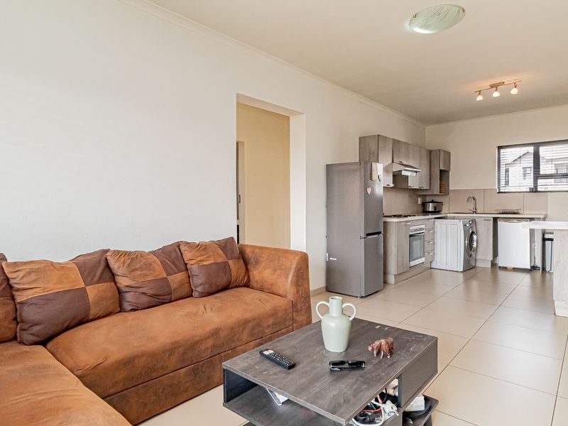 Open-plan living area featuring a functional kitchen with built-in cabinetry, integrated appliances, and a breakfast counter, seamlessly connected to the lounge space.