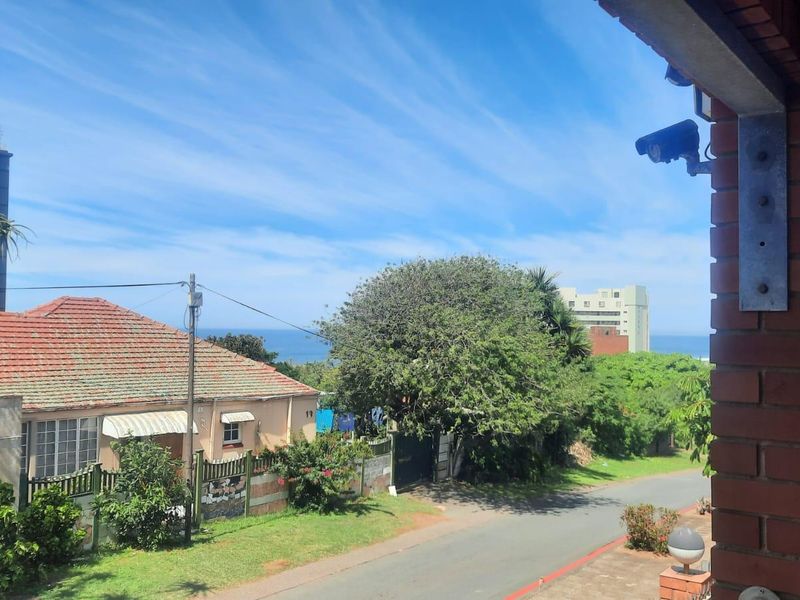 Elevated view overlooking the street and surrounding neighbourhood with a glimpse of the ocean in the distance.