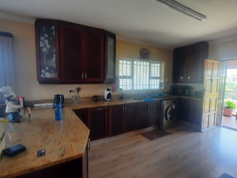 A functional kitchen featuring dark wood cabinetry, granite countertops, and direct access to an outdoor balcony area.