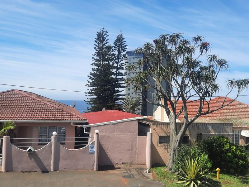 Front elevation of a residential property featuring a tiled roof, boundary wall with metal gate, and driveway access.