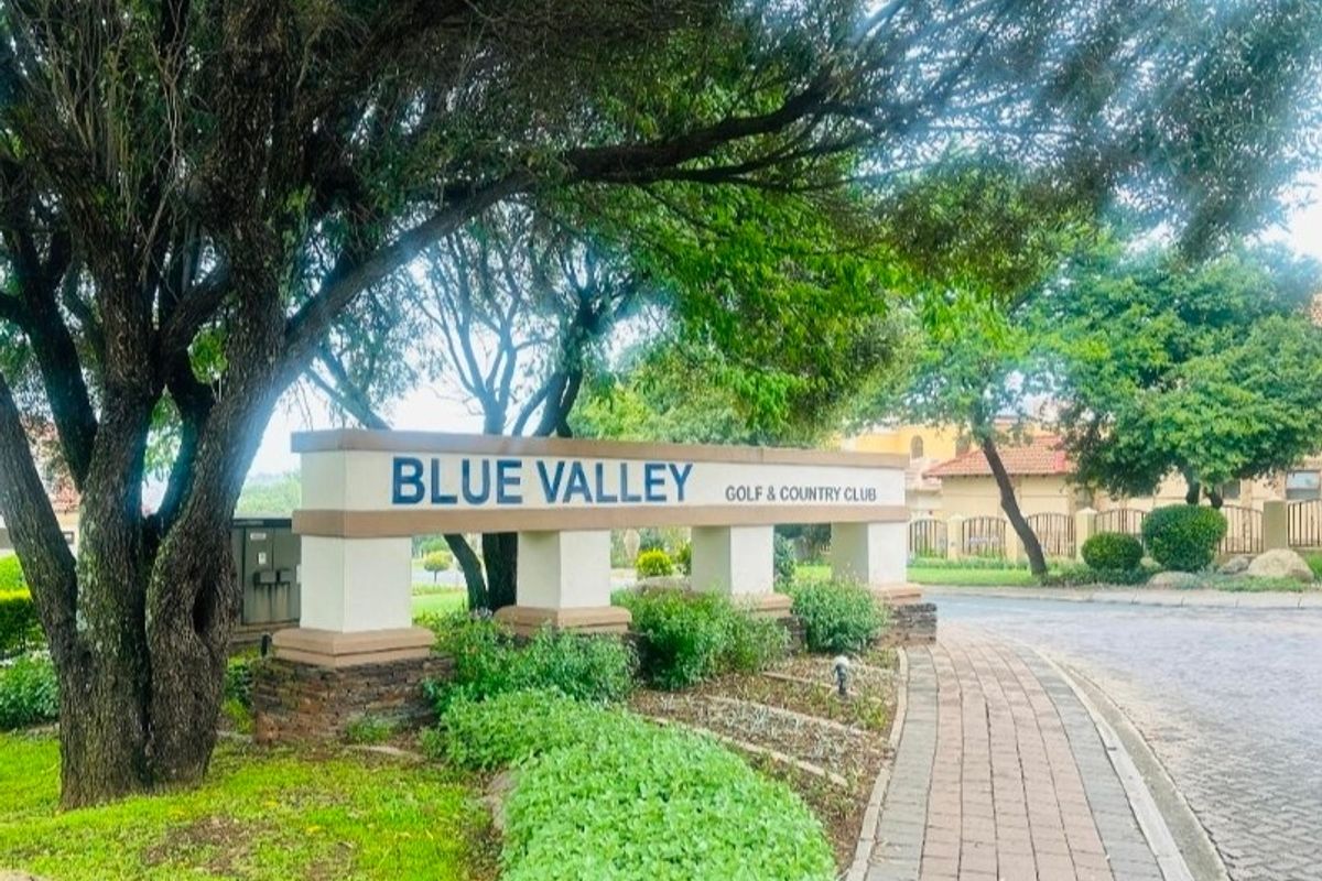 Entrance view of the Blue Valley Golf & Country Club featuring established landscaping, paved walkways, and clear estate signage.