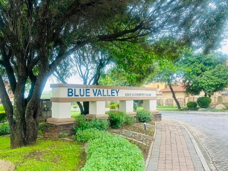 Entrance view of the Blue Valley Golf & Country Club featuring established landscaping, paved walkways, and clear estate signage.