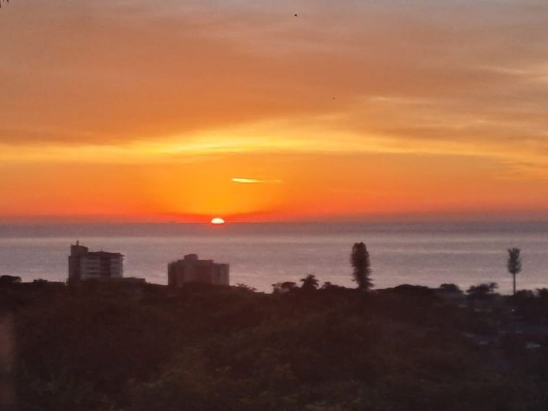 A scenic sunset view overlooking the ocean and coastal landscape.