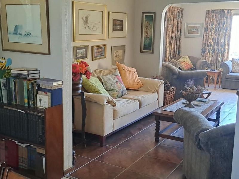 A cozy living room featuring tiled flooring and an arched entryway leading to an adjacent seating area.