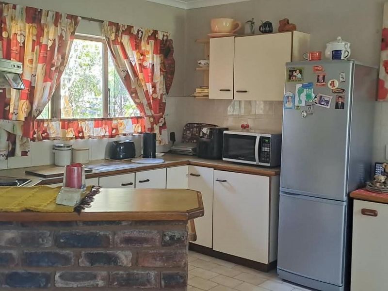 A functional kitchen featuring built-in cabinetry, a brick breakfast bar, and tiled backsplash, offering a dated aesthetic with potential for modern updates.