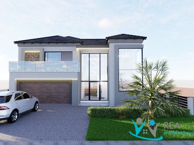 Modern double-storey residential facade featuring a double garage, glass balcony, and striking full-height entrance glazing with contemporary stone and render finishes.