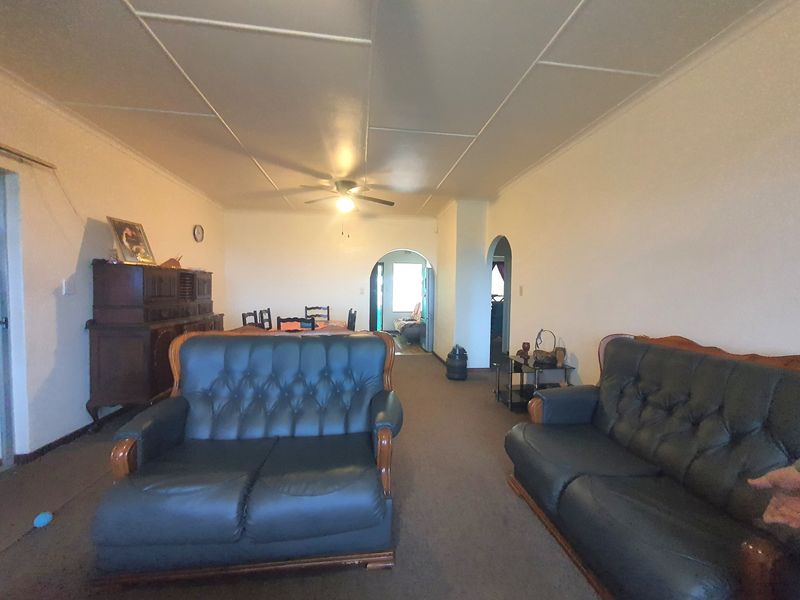 Spacious living area featuring a ceiling fan and traditional archway transitions, offering a dated interior ready for modernization.