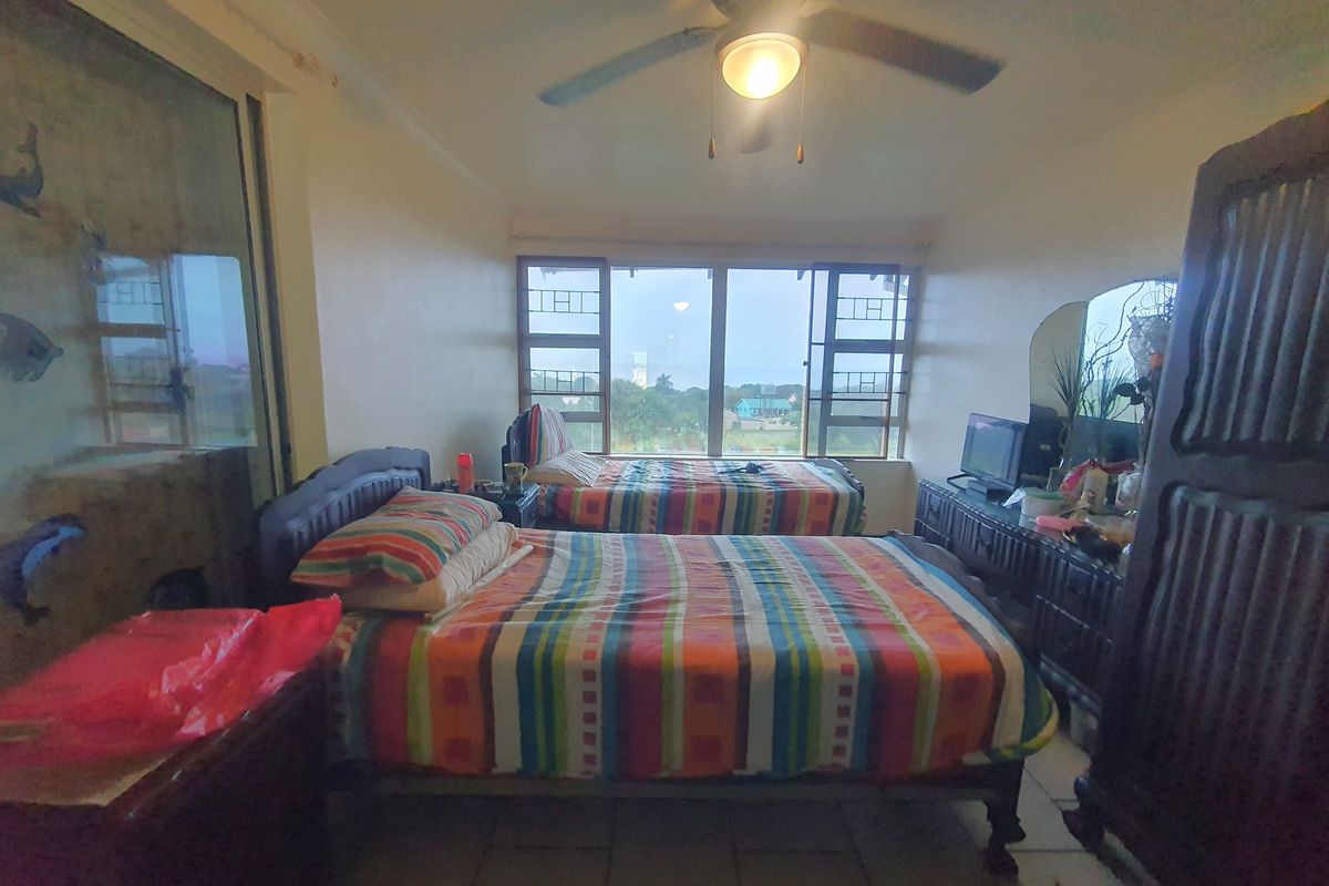 A bedroom featuring tiled flooring, a ceiling fan, and large windows providing natural light and exterior views.