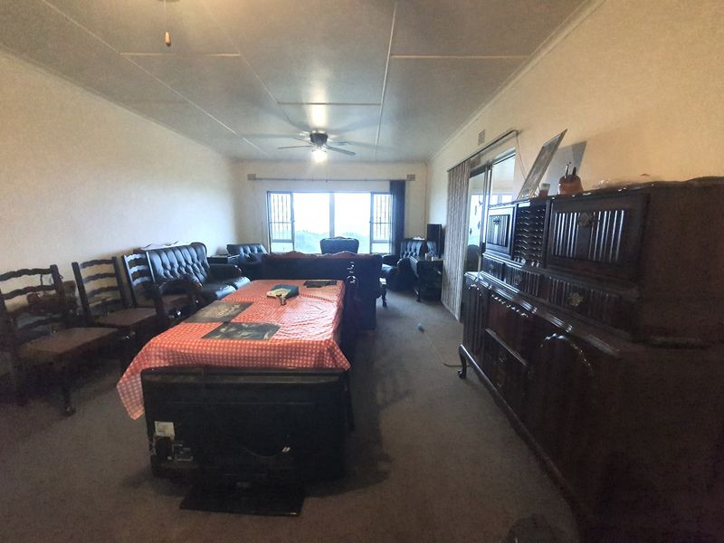 Spacious living area featuring carpeted flooring, a ceiling fan, and large sliding glass doors providing natural light and access to the exterior.