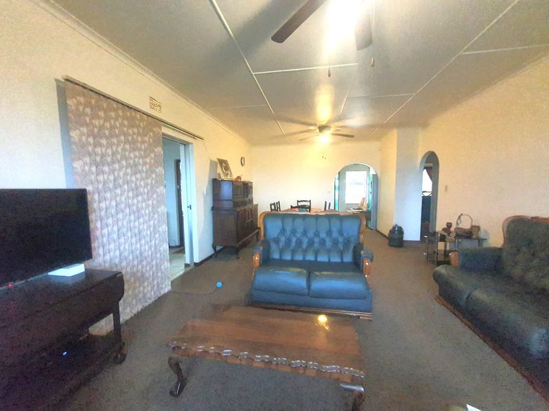 Spacious living area featuring an archway, ceiling fan, and carpeted flooring, offering a functional layout with potential for modernization.