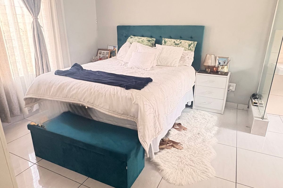 A well-lit bedroom featuring tiled flooring and direct access to an en-suite bathroom with a built-in basin.
