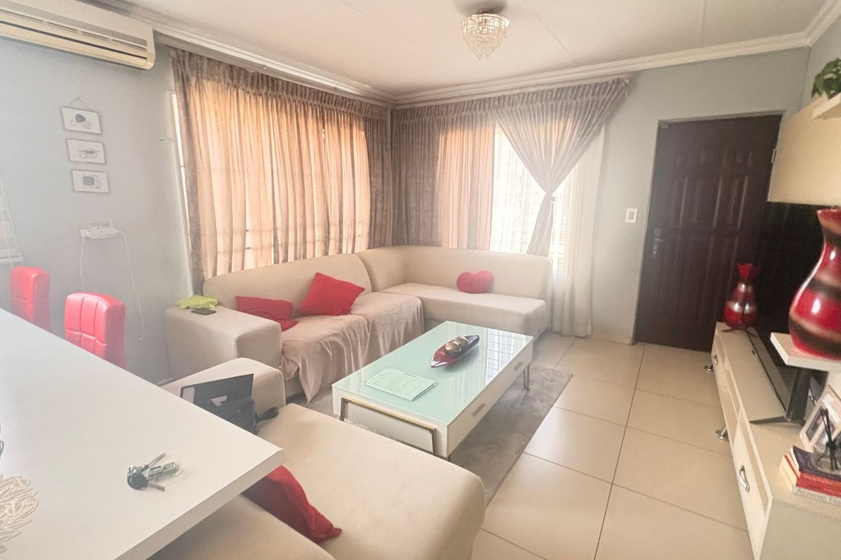 A comfortable living room featuring tiled flooring, cove molding, and a wall-mounted air conditioning unit.