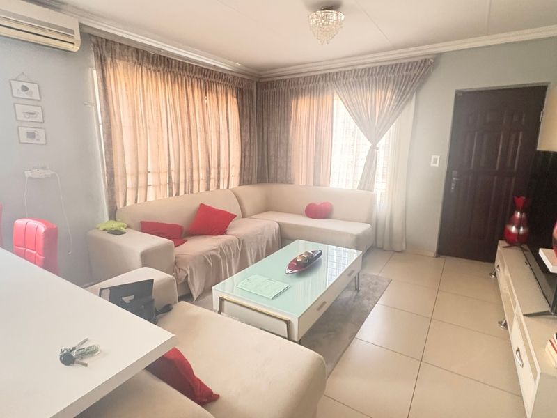 A comfortable living room featuring tiled flooring, cove molding, and a wall-mounted air conditioning unit.