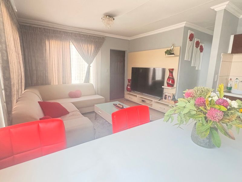 Open-plan living area featuring a combined lounge space and compact kitchen with built-in cabinetry and media unit.