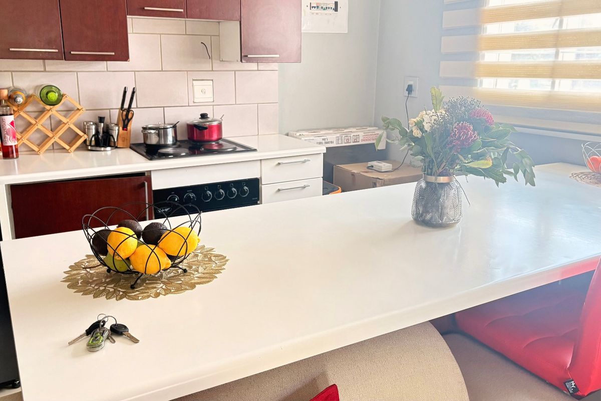 A functional kitchen featuring dark wood cabinetry, a white stone countertop, a breakfast bar, and a built-in electric hob and oven.
