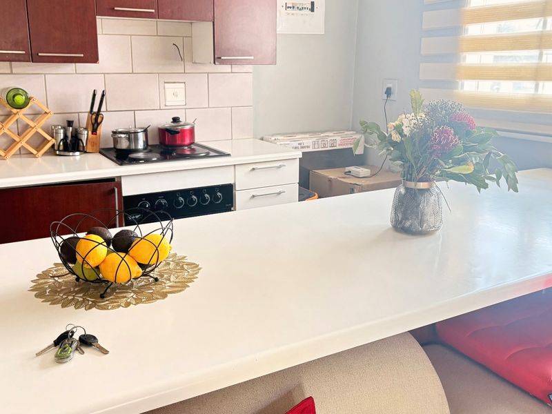 A functional kitchen featuring dark wood cabinetry, a white stone countertop, a breakfast bar, and a built-in electric hob and oven.