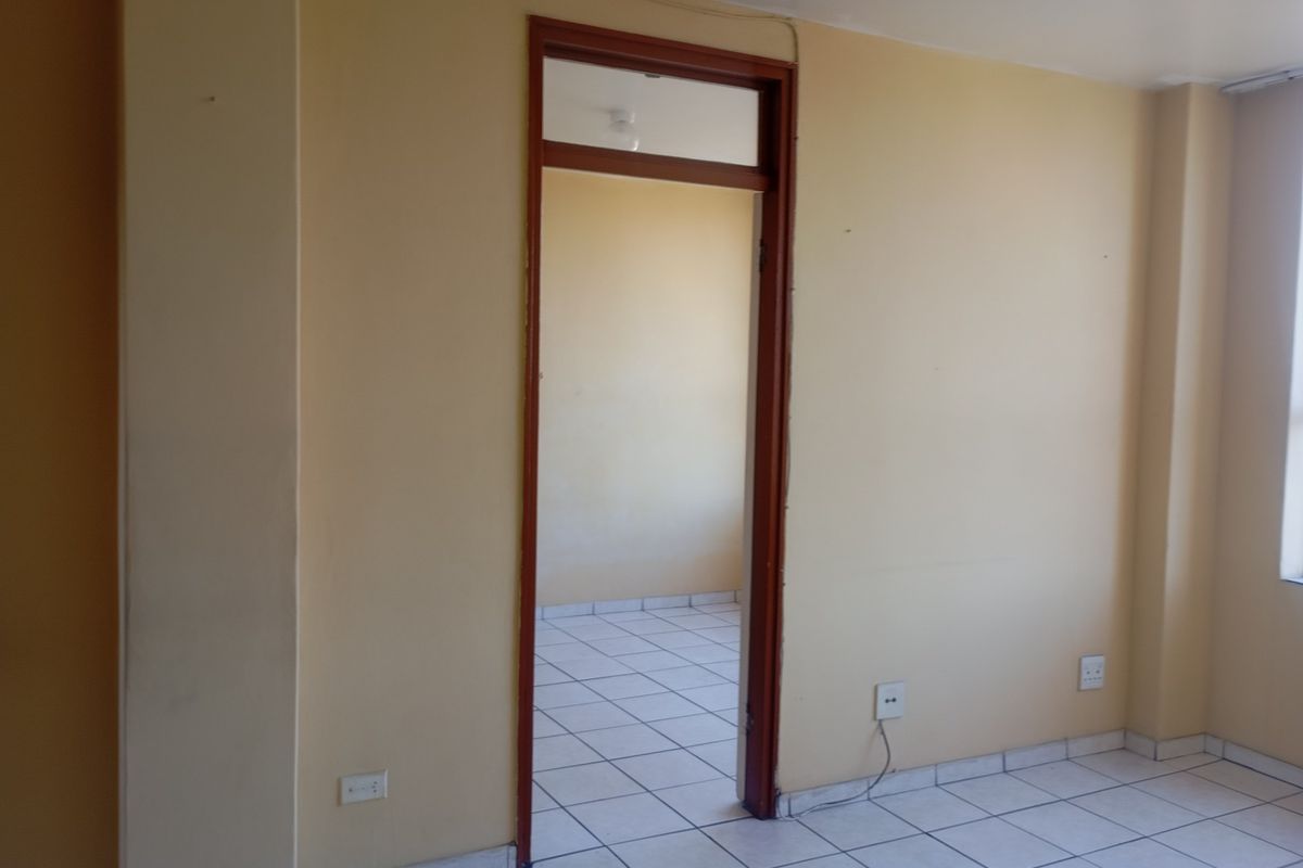 An empty bedroom featuring tiled flooring, neutral wall paint, and a doorway leading to an adjacent space.