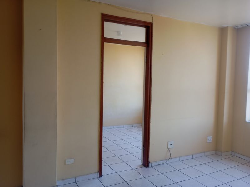 An empty bedroom featuring tiled flooring, neutral wall paint, and a doorway leading to an adjacent space.