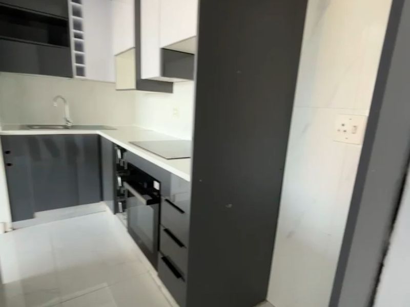 Modern kitchen featuring sleek two-tone cabinetry, integrated oven, cooktop, and high-quality tiled finishes in a clean, contemporary layout.