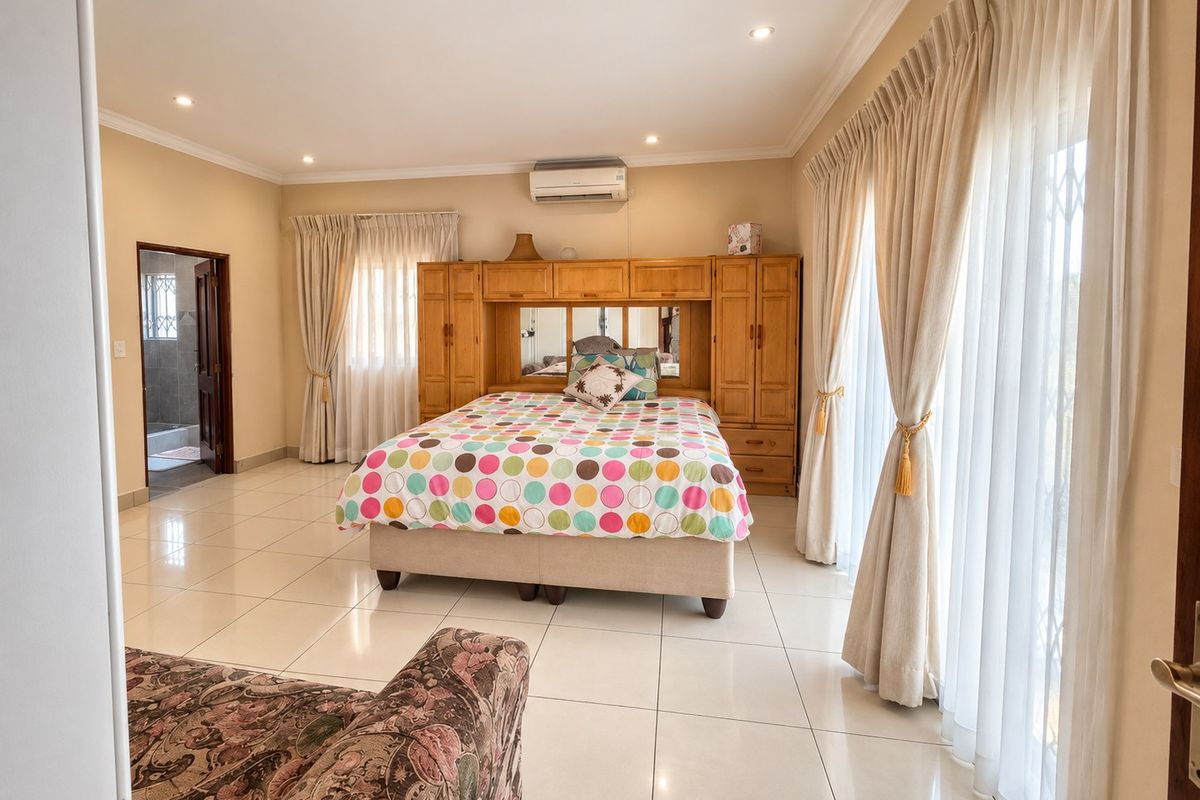 Spacious bedroom featuring tiled flooring, built-in wooden cupboards, air conditioning, and large sliding doors providing access to natural light.