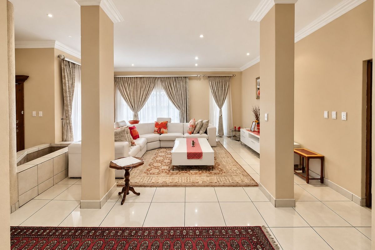 Spacious living room featuring tiled flooring, crown molding, recessed lighting, and structural columns, creating an open and well-defined living area.