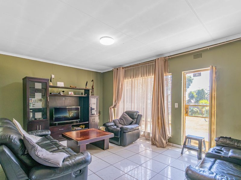 A living room featuring tiled flooring, a flush mount ceiling light, and a sliding glass door providing access to the exterior.