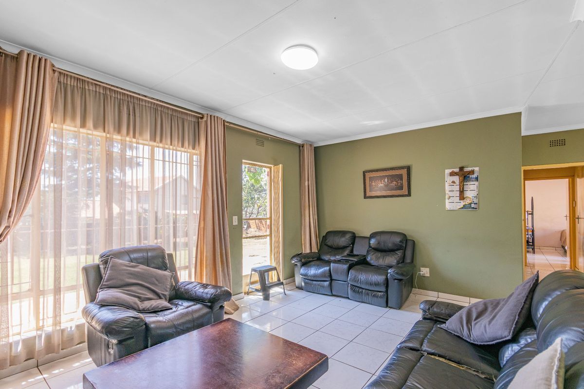 A living room featuring tiled flooring, a large sliding glass door providing natural light, and direct access to the outdoor area.