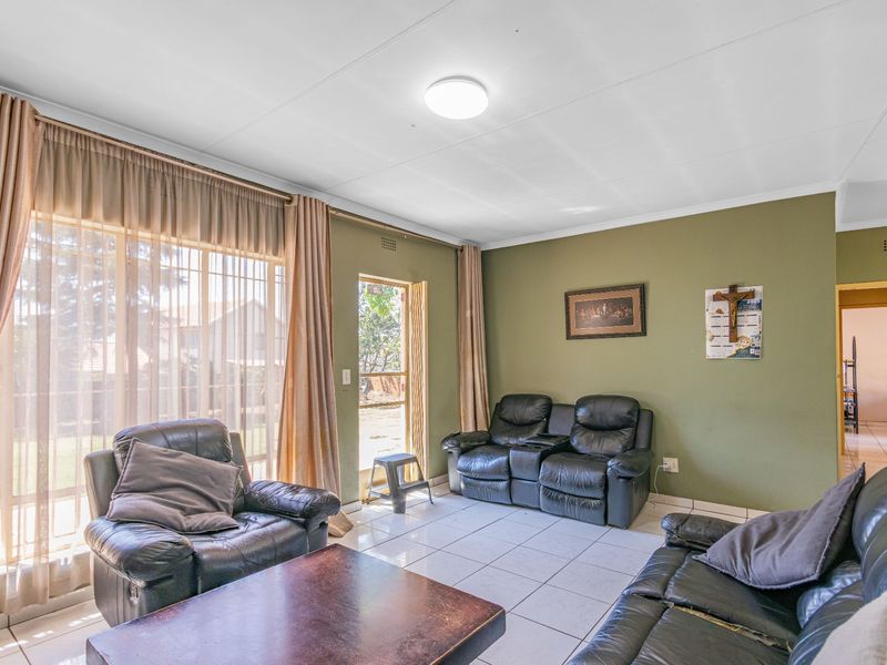 A living room featuring tiled flooring, a large sliding glass door providing natural light, and direct access to the outdoor area.