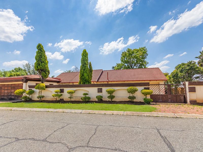 Front exterior view of a residential property featuring a tiled roof, boundary wall, and gated driveway access.