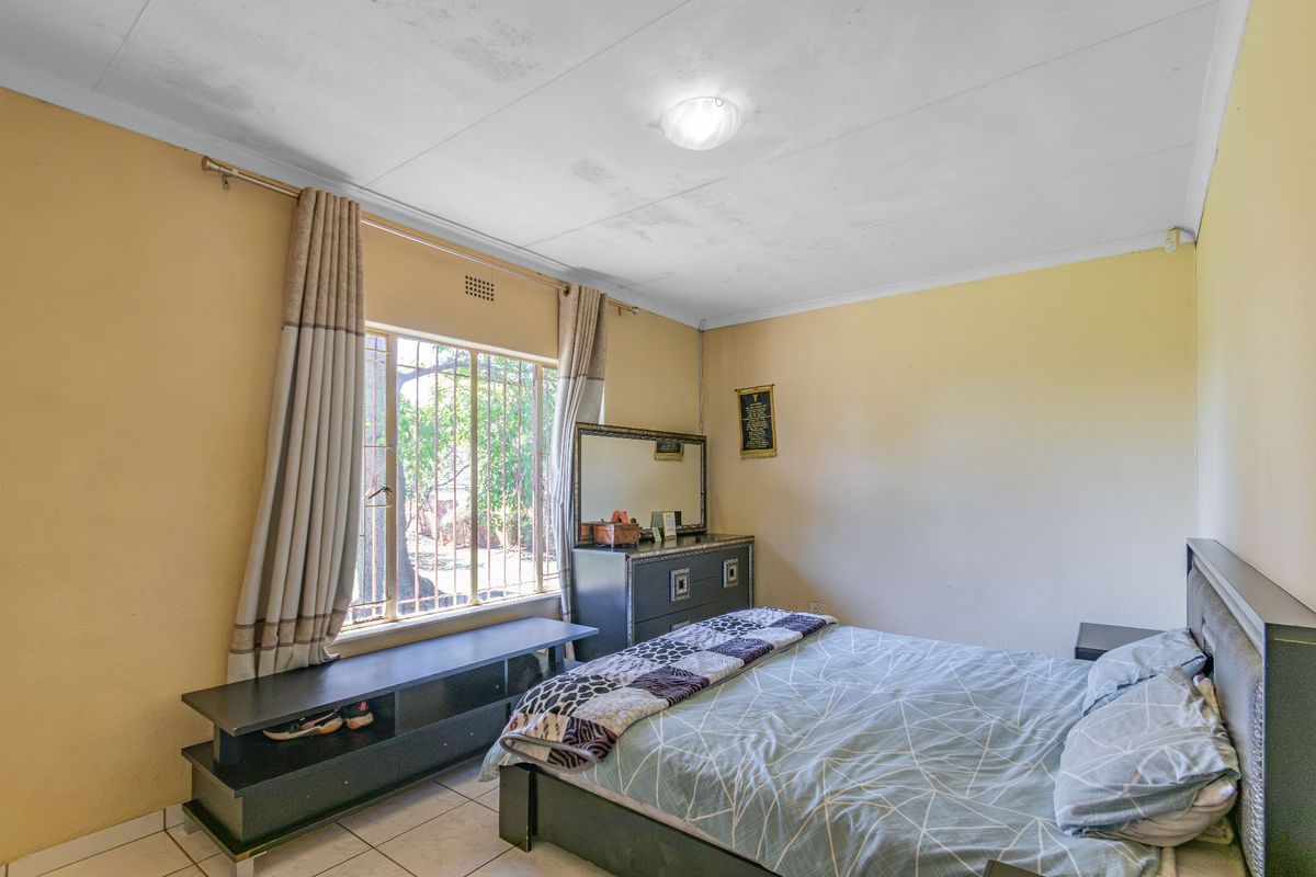 A bedroom featuring tiled flooring and a window with security bars. The room requires cosmetic updates to the ceiling and wall finishes.