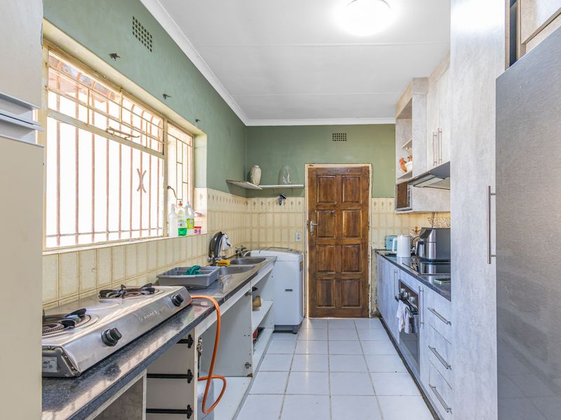 A functional galley-style kitchen featuring built-in cabinetry, a double sink, and integrated cooking appliances, requiring cosmetic updates to modernize the space.