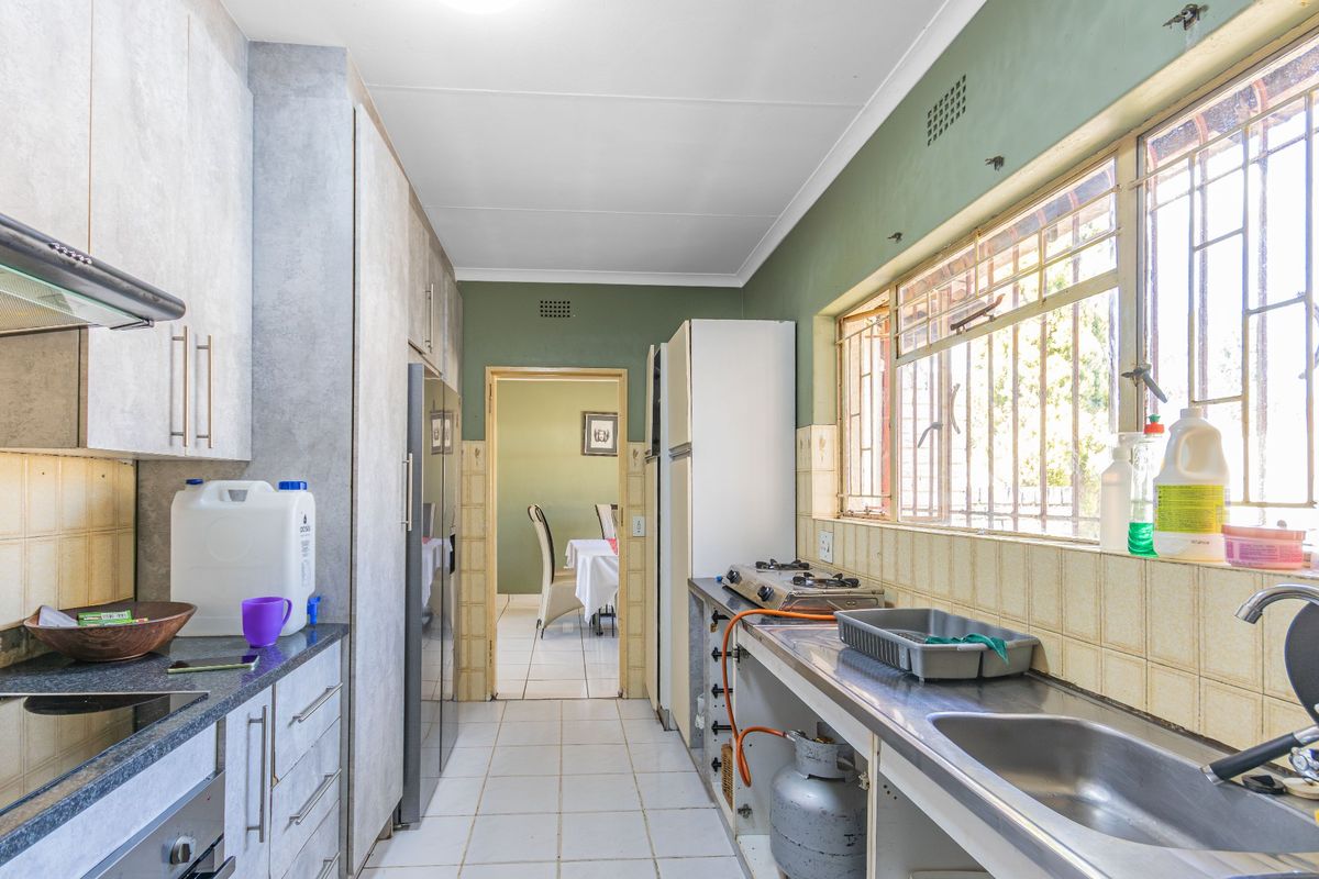A functional kitchen featuring built-in cabinetry, a stainless steel sink, and a gas hob, with direct access to the adjacent dining area.