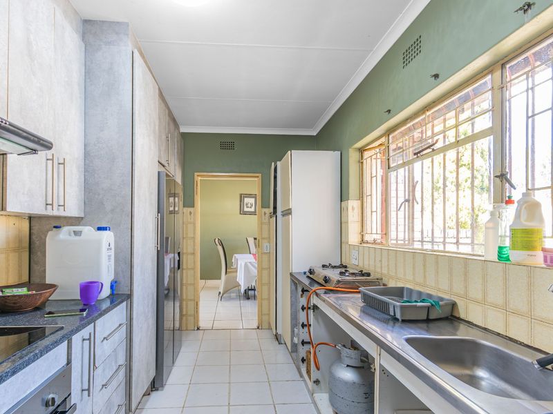 A functional kitchen featuring built-in cabinetry, a stainless steel sink, and a gas hob, with direct access to the adjacent dining area.