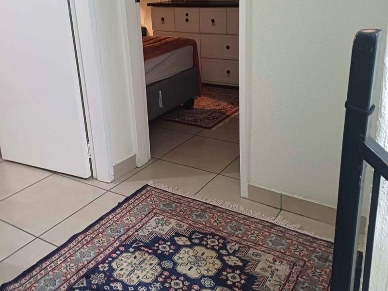 A view from a hallway looking into a bedroom, featuring tiled flooring and standard internal door frames.