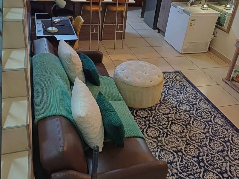 Open plan living area featuring a kitchen with built-in cabinetry and island, seamlessly flowing into the lounge space with tiled flooring throughout.