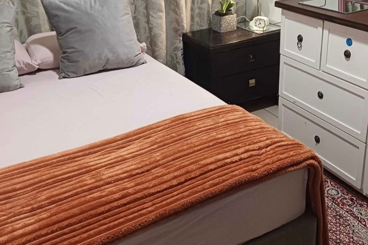 A bedroom interior featuring standard finishes, curtains, and tiled flooring.